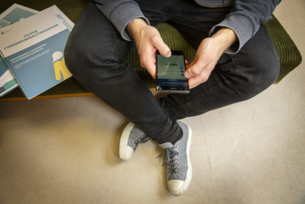 En ung person sidder og kigger på en mobil