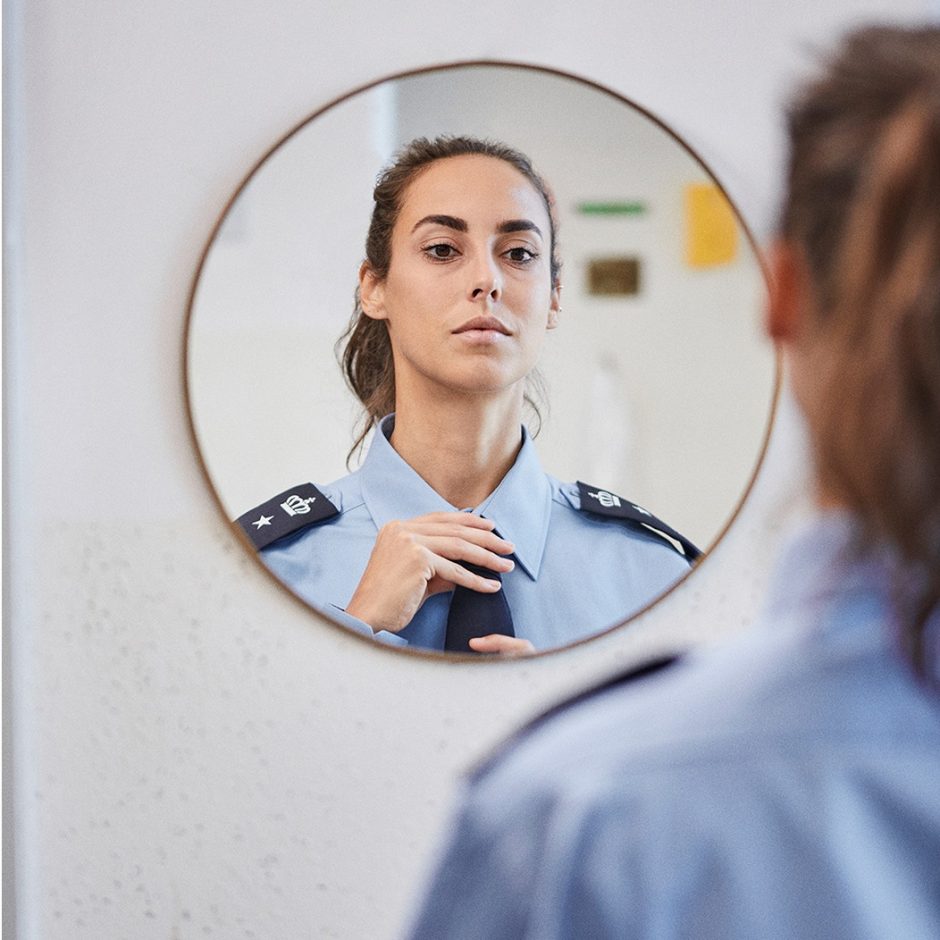 En fængselsbetjent ser sig i spejlet og retter på slipset